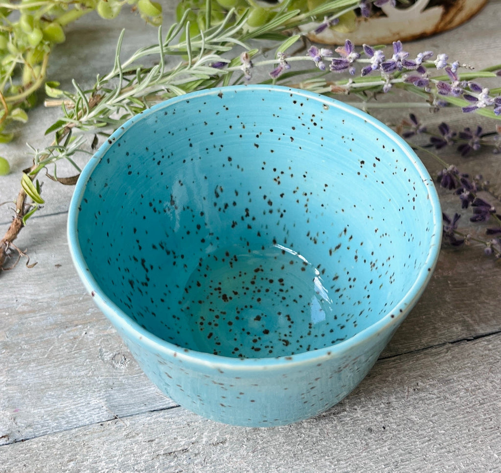 Handmade ceramic bowl with glossy turquoise glaze and dark speckled clay