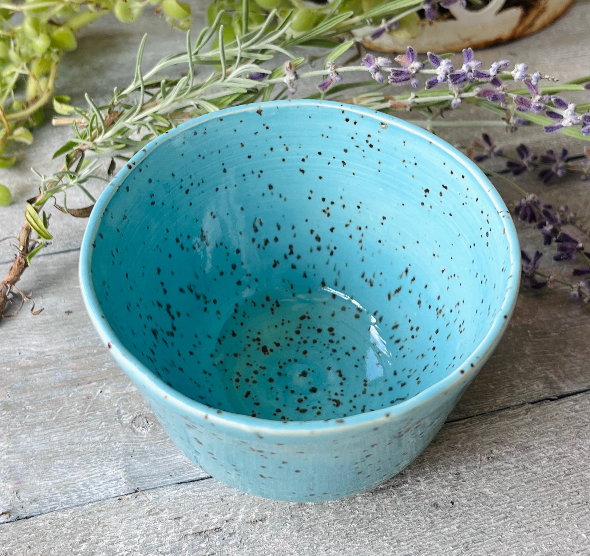 Handmade ceramic bowl with glossy turquoise glaze and dark speckled clay