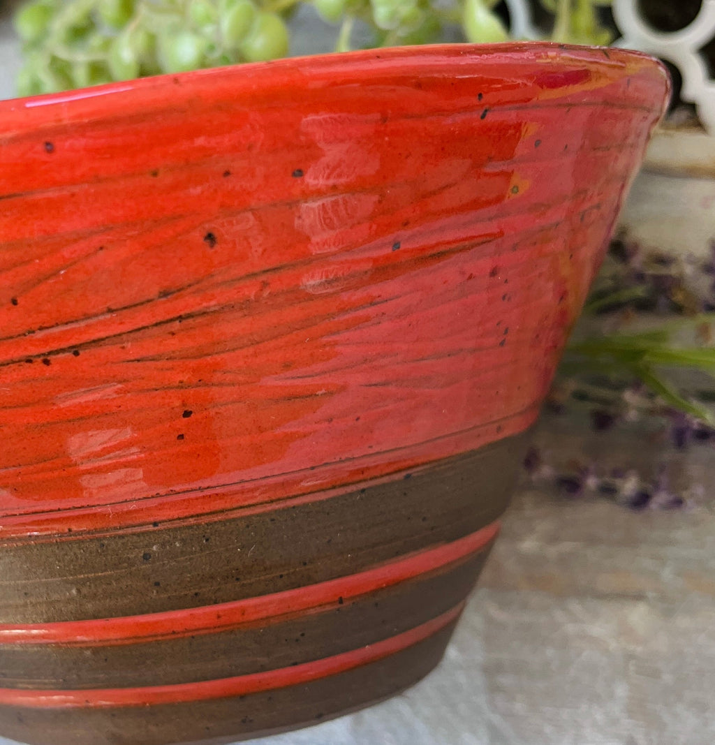 Close-up of fiery red-orange glaze detail on handmade ceramic bowl