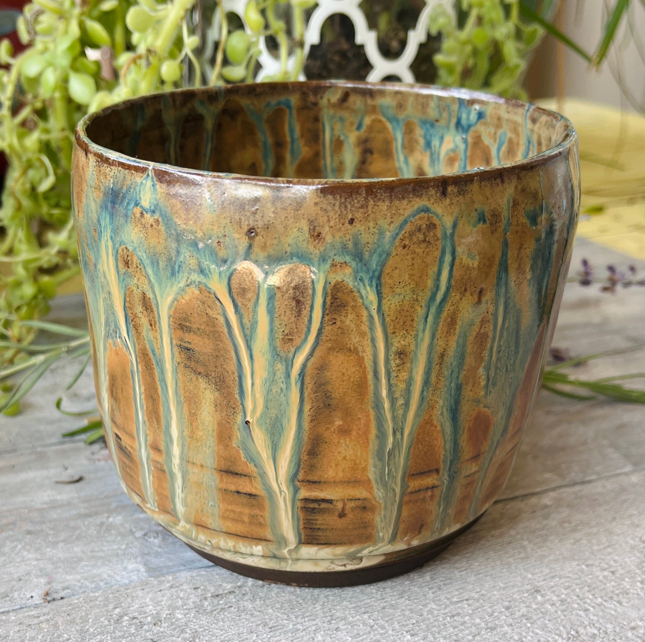 Handmade ceramic vessel with hand-carved vertical ridges and amber teal drip glaze