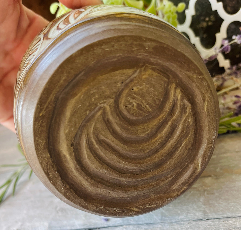 Bottom of handmade ceramic vessel showing hand-carved spiral detail