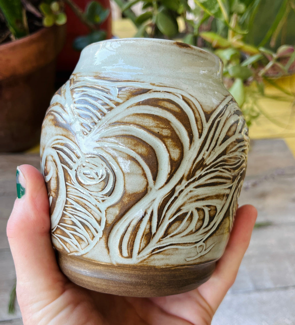 Handmade ceramic vessel with hand-carved feather and wave motifs and celadon glaze